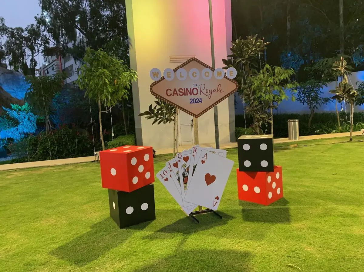 Giant dice and playing-card décor with a welcome sign at dusk