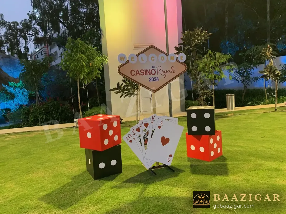 Giant dice and playing-card décor with a welcome sign at dusk