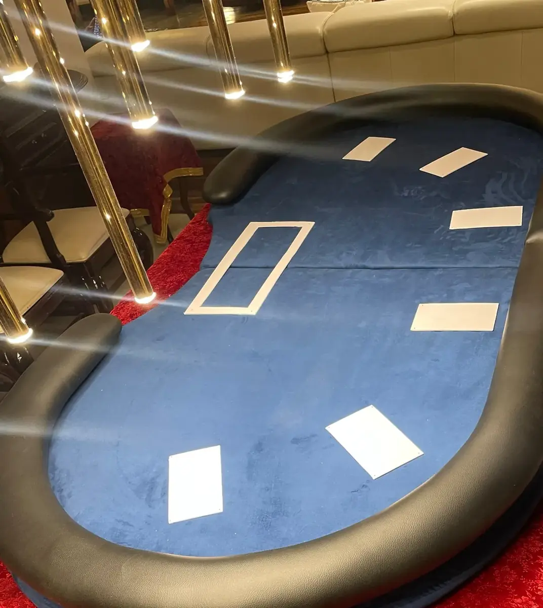 Blue poker table with padded rail under warm lights